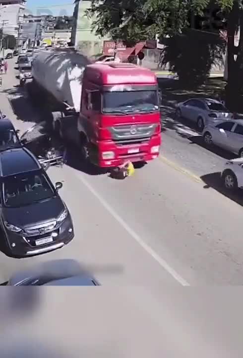 پرت شدن موتورسوار زیر چرخ‌های تریلی بعد از اشتباه فاحش راننده سواری!