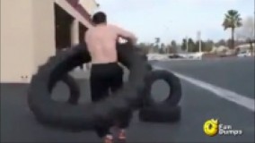 چرخاندن لاستیک تراکتور دور کمر توسط مردی با قدرت بدنی بالا